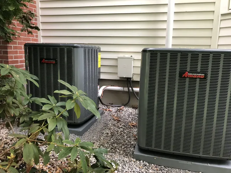 Amana central air conditioners installed beside a brick home by A.J. LeBlanc Heating in Southern NH