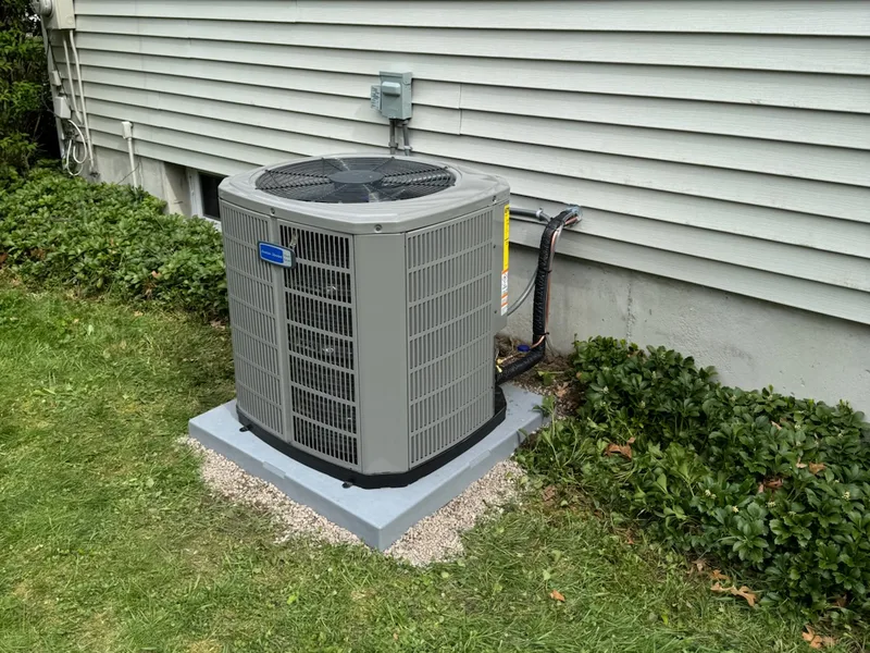 American Standard central air conditioner condenser installed on a concrete pad beside a Southern NH home by A.J. LeBlanc Heating