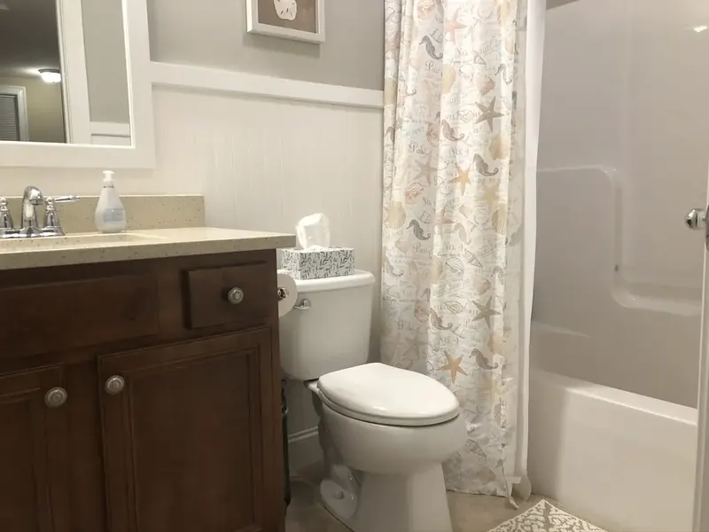 Bathroom remodel with beadboard wainscoting, brown vanity, and shower tub combo installed by A.J. LeBlanc Heating in a Southern NH home