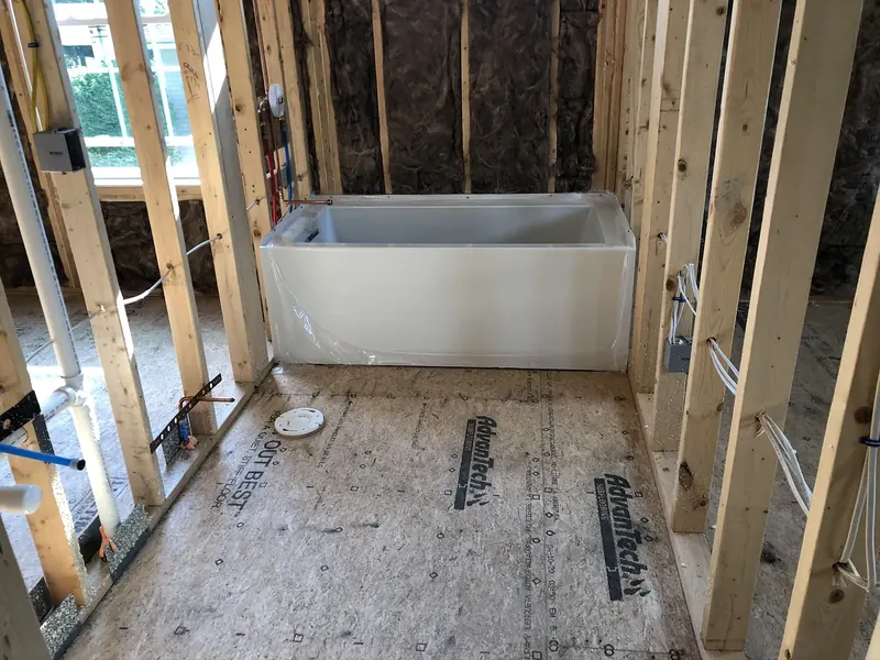 Bathtub set into wall framing during a new construction bathroom rough-in with insulated exterior wall and AdvanTech subfloor, by A.J. LeBlanc Heating in Southern NH