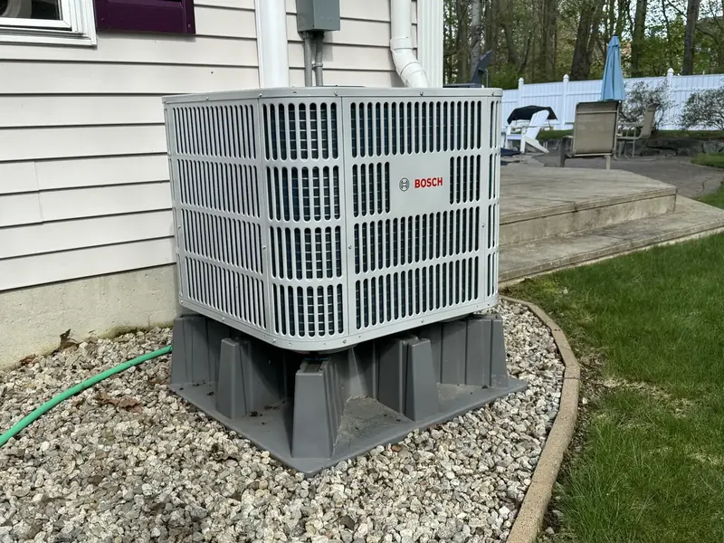 Bosch central air conditioner installed beside a backyard patio by A.J. LeBlanc Heating in Southern NH