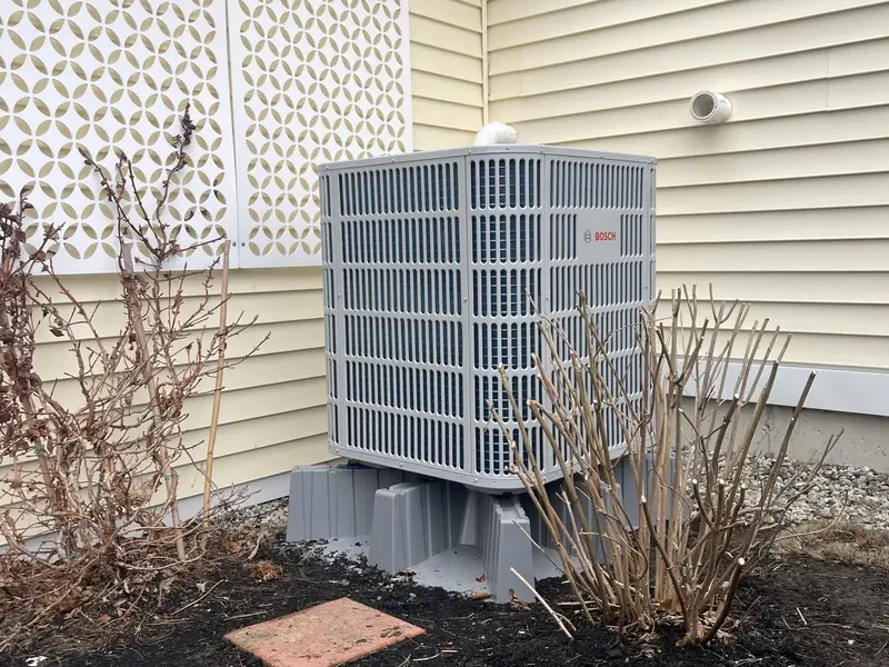 Bosch outdoor condenser installed in a landscaped bed by A.J. LeBlanc Heating in Southern NH