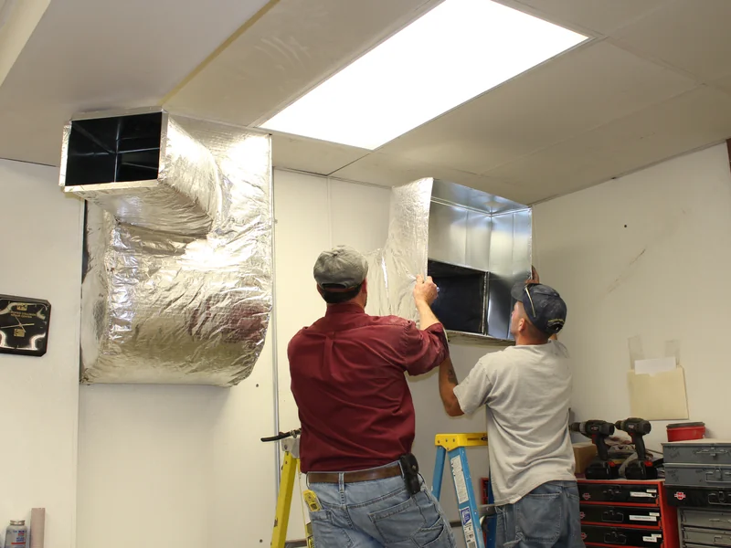A.J. LeBlanc Heating technicians installing insulated ductwork in a commercial space