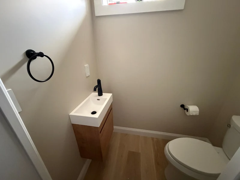 Compact bathroom viewed from the doorway, with a floating vanity, black fixtures and white toilet
