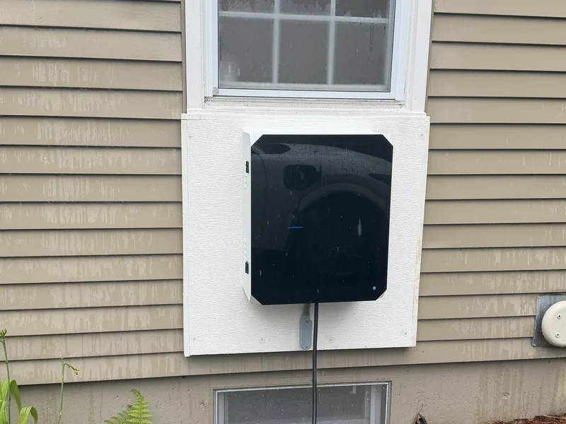 Weatherproof outdoor EV charging station enclosure mounted on the exterior wall of a Southern NH home by A.J. LeBlanc Heating