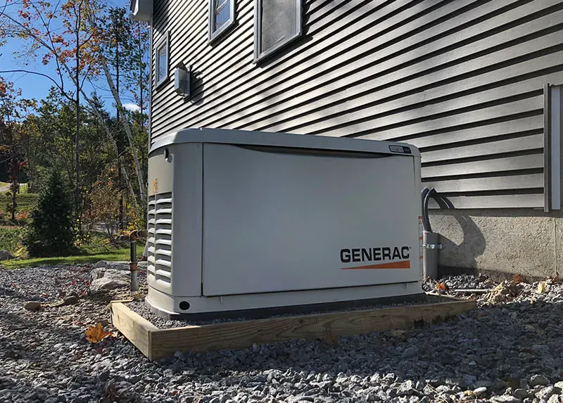 Generac home standby generator on a residential gravel pad as an alternative to battery backup, installed by A.J. LeBlanc Heating in Southern NH
