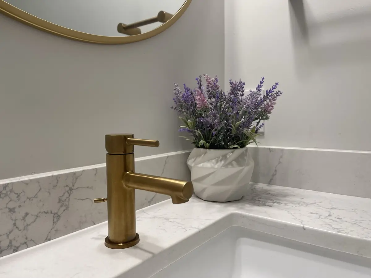 Brushed gold bathroom vanity faucet installed on a quartz countertop by A.J. LeBlanc Heating in a Southern NH bathroom remodel