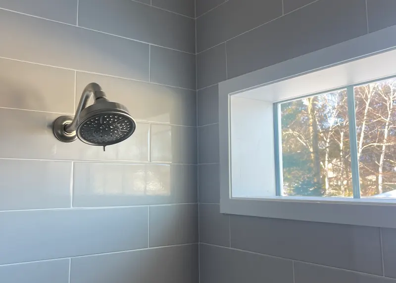 Gray subway tile shower with moen shower head and window