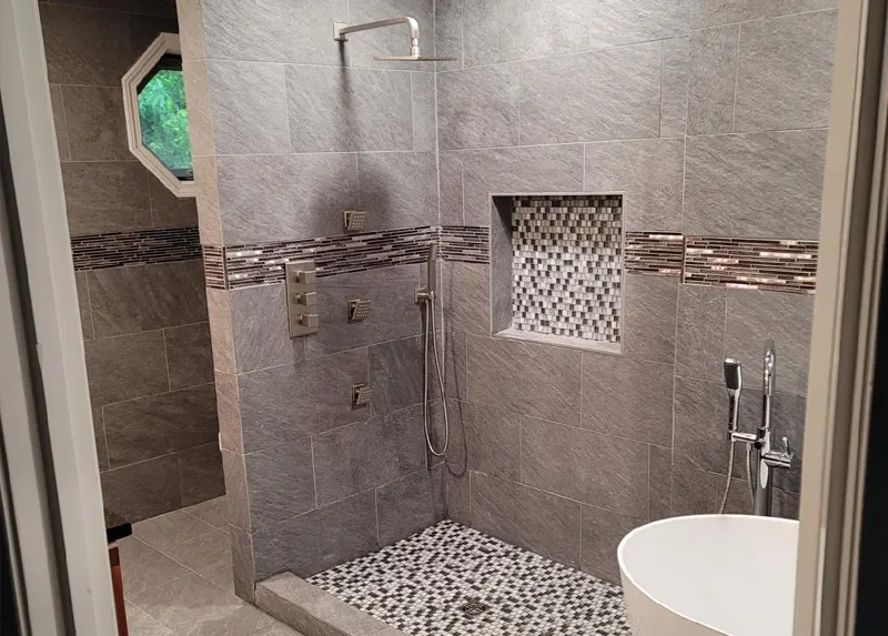 Gray tile shower with soap niche and free standing tub