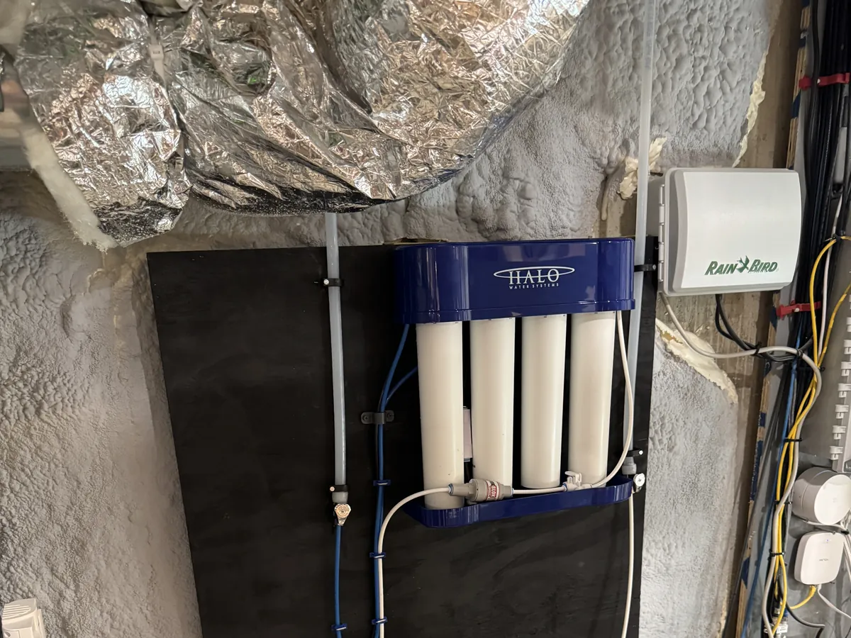 HALO multi-stage water treatment system mounted on a black backer board in a spray-foam insulated Southern NH mechanical room, installed by A.J. LeBlanc Heating