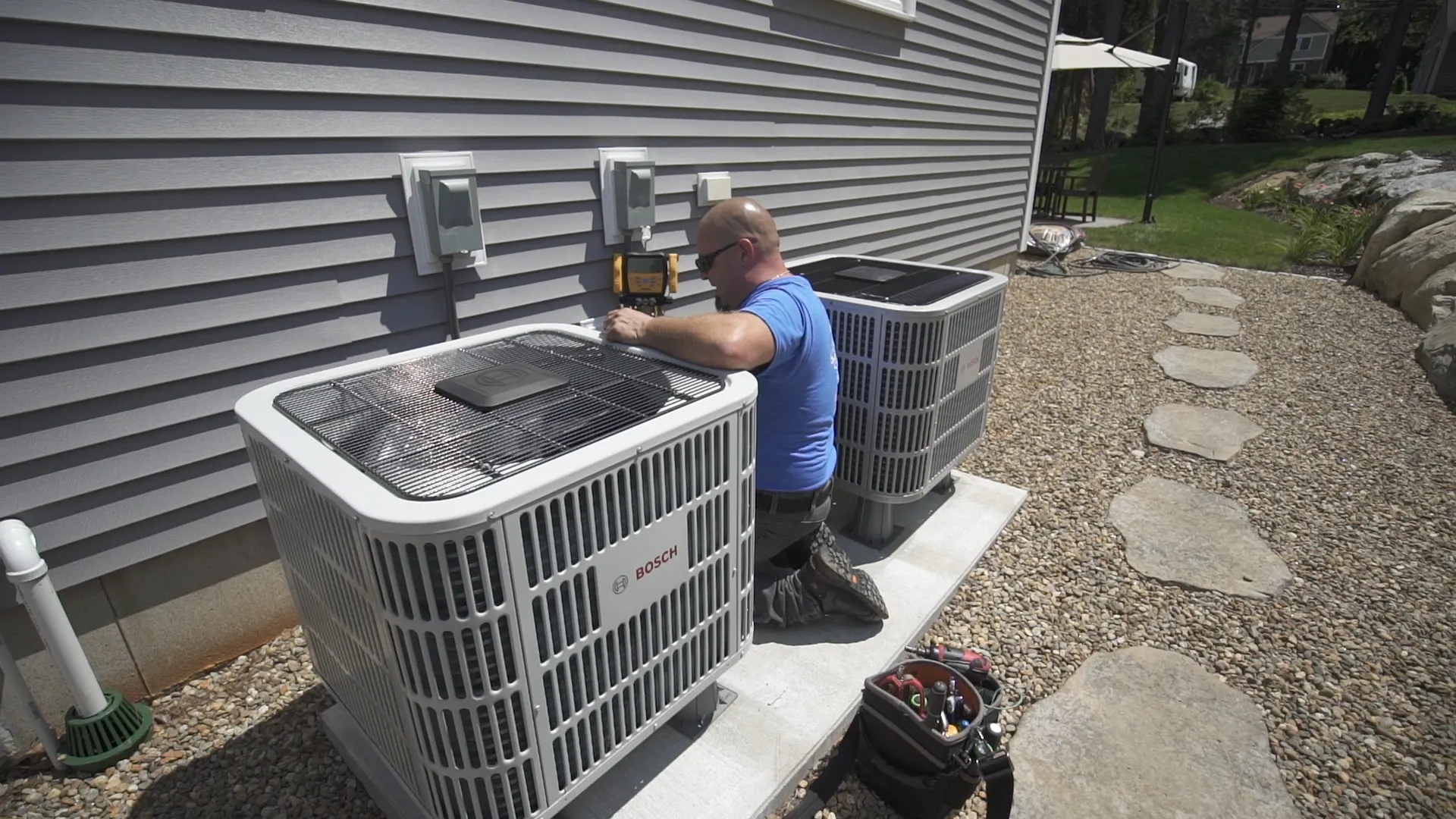 A.J. LeBlanc Heating technician servicing outdoor condenser units at a Southern NH home, the kind of installation eligible for financing through Wells Fargo Home Projects
