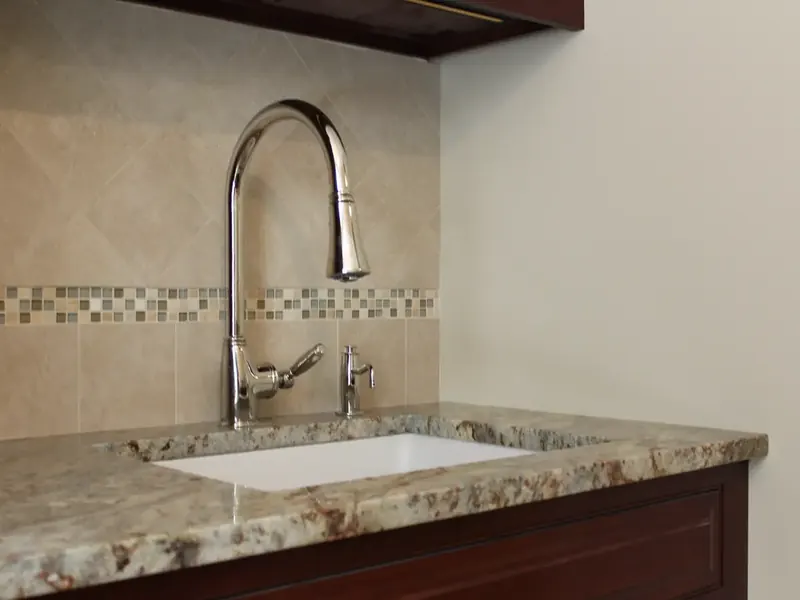 Chrome pull-down kitchen faucet with glass mosaic backsplash tile installed by A.J. LeBlanc Heating in a Southern NH home