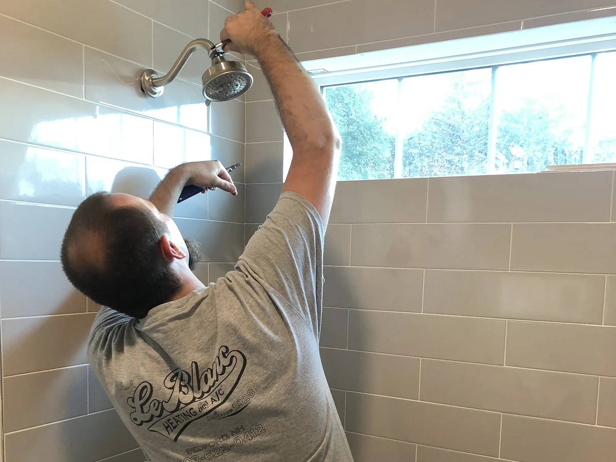A.J. LeBlanc licensed plumber installing a shower head in a southern New Hampshire home