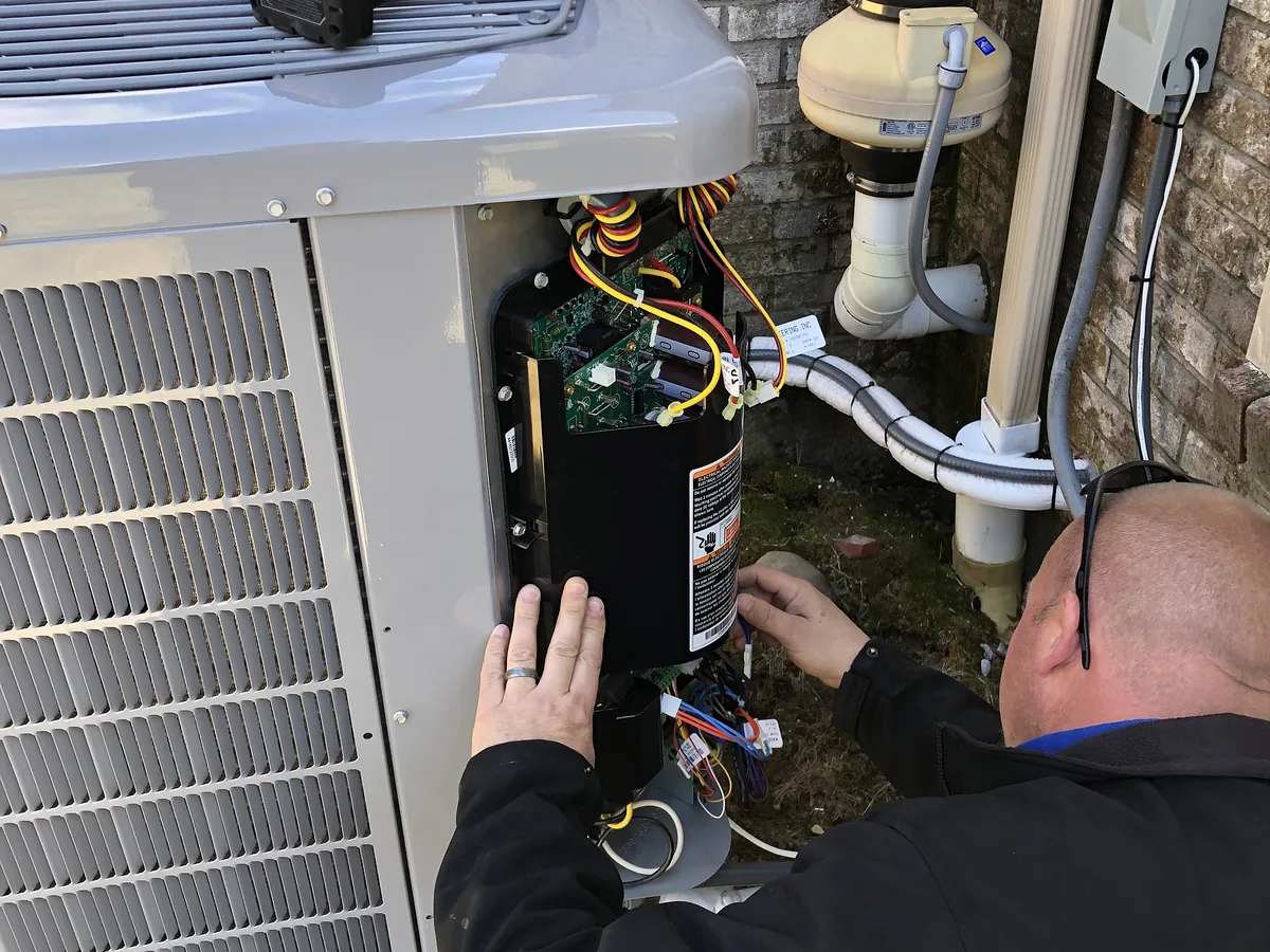A.J. LeBlanc Heating technician checking electrical components in an outdoor air-conditioning condenser