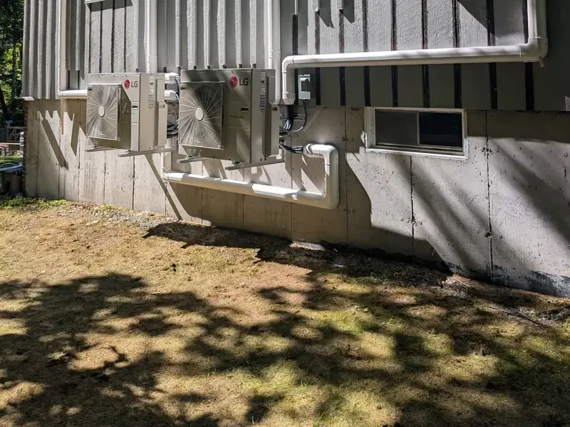 Two LG ductless mini split outdoor units installed on a board-and-batten Southern NH home
