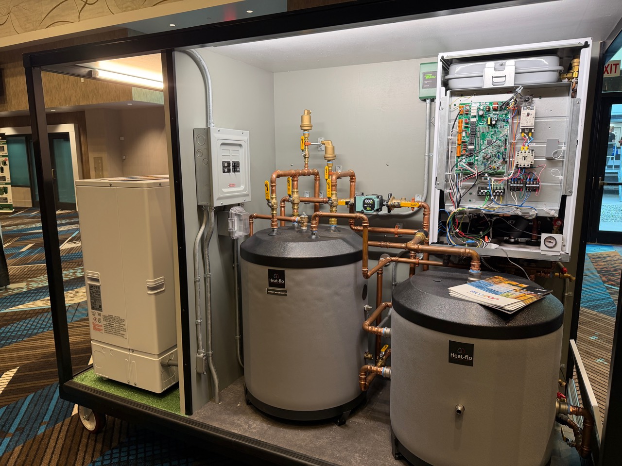 Trade-show hydronic display with open indoor equipment, copper piping and two Heat-flo tanks.