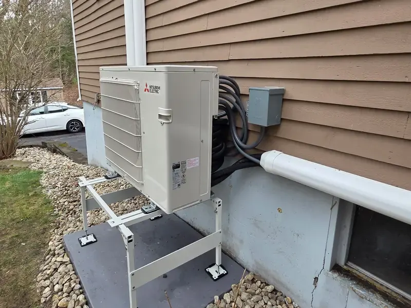 Mitsubishi outdoor mini split heat pump mounted on a stand at a Southern NH home, installed by A.J. LeBlanc Heating