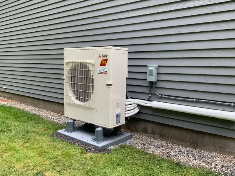 Mitsubishi Electric ductless mini split outdoor unit installed against gray siding at a Southern NH home