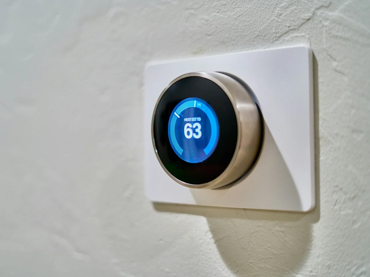 Google Nest Learning Thermostat with a blue display on a white wall