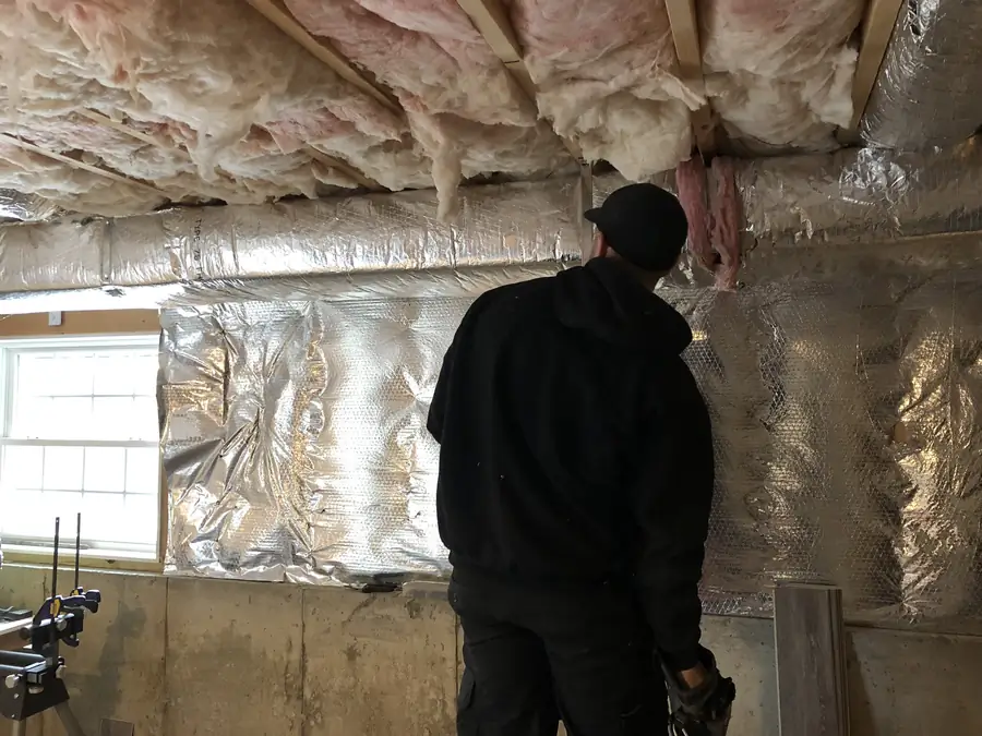 A.J. LeBlanc Heating technician installing insulated ductwork in a new construction lower level in Southern NH