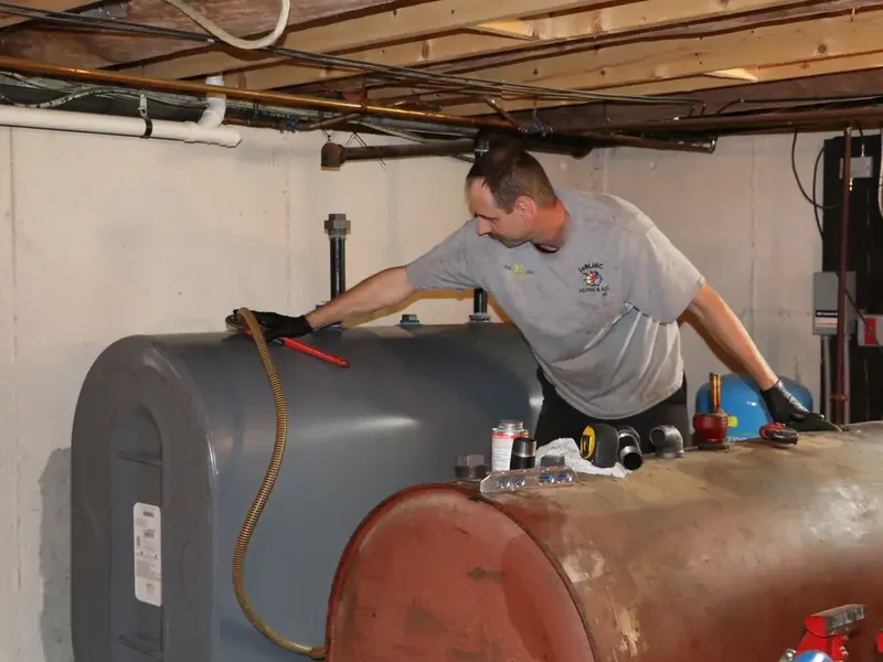 A.J. LeBlanc Heating technician installing a new 275-gallon oil tank next to the old tank being removed in a Southern NH basement