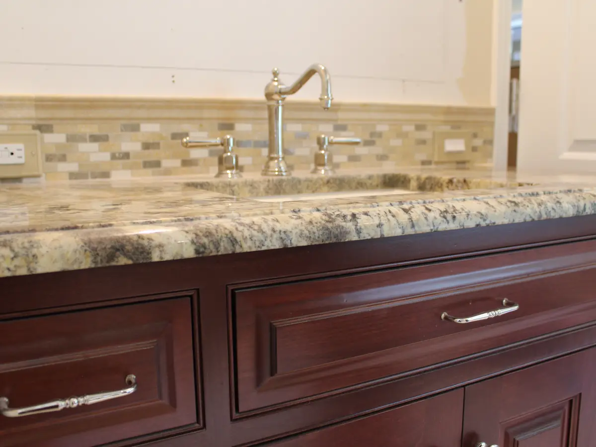 Polished nickel widespread bridge faucet on a granite vanity counter installed by A.J. LeBlanc Heating in a Southern NH bathroom