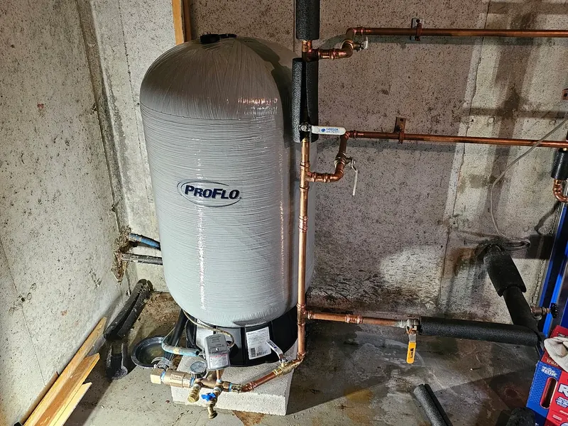 ProFlo well water pressure tank installed in a Southern NH basement with copper supply manifold, drain valves, and concrete-wall mechanical room by A.J. LeBlanc Heating