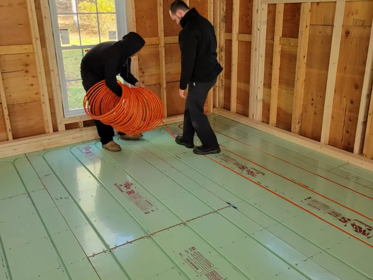 A.J. LeBlanc Heating technicians installing radiant floor heating PEX tubing on Warmboard panels in a new construction framed structure in Southern NH