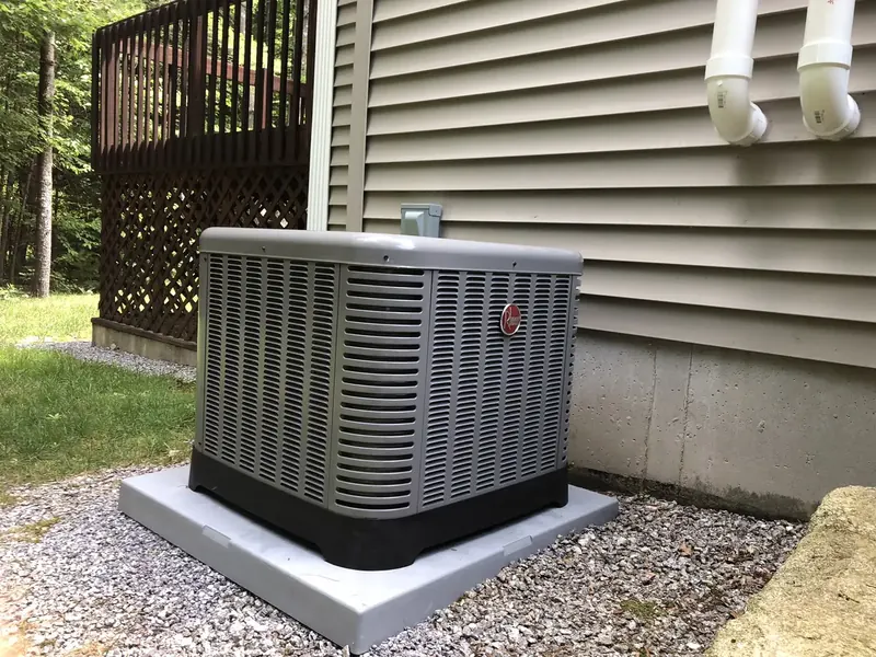 Rheem central air conditioner condenser installed beside a backyard deck by A.J. LeBlanc Heating in Southern NH