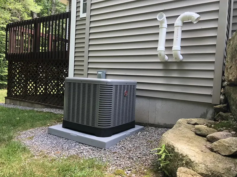 Rheem central air conditioner condenser installed on a gravel pad by A.J. LeBlanc Heating at a Southern NH home