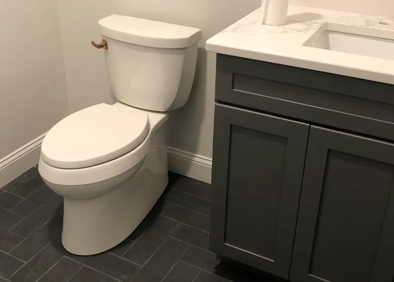 Skirted Kohler toilet with herringbone tile floor