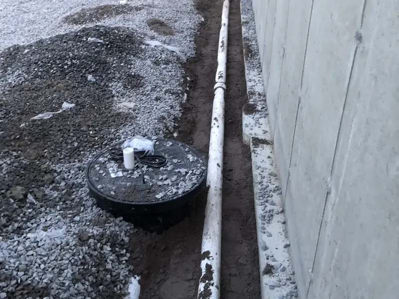 Sump pump basin and PVC discharge pipe installed in a new construction foundation by A.J. LeBlanc Heating in Southern NH
