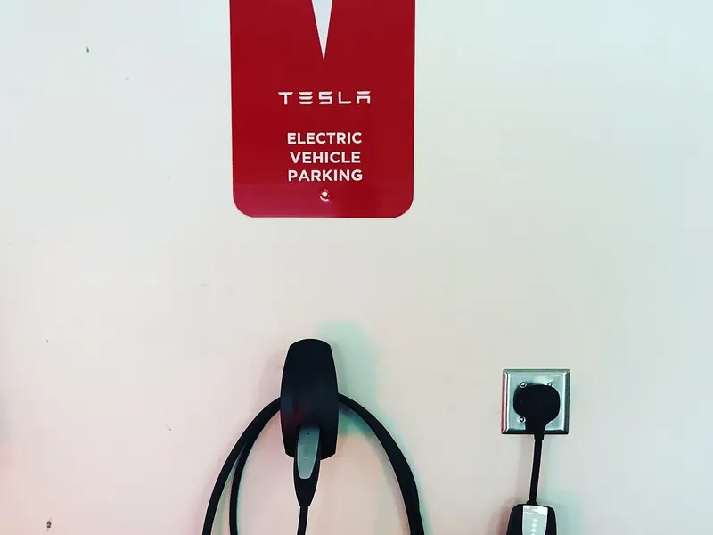 Tesla Mobile Connector at a NEMA 14-50 outlet with branded EV parking sign in a Southern NH garage