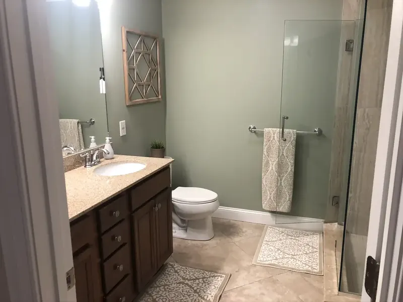 Bathroom remodel with brown wood vanity, granite counter, and walk-in glass shower installed by A.J. LeBlanc Heating in a Southern NH home