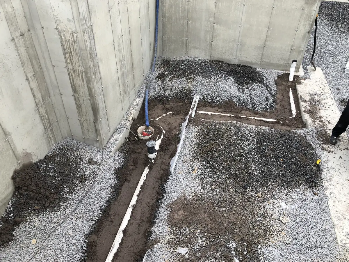 Underslab PVC drain line rough-in laid in trenches inside a new construction foundation by A.J. LeBlanc Heating in Southern NH