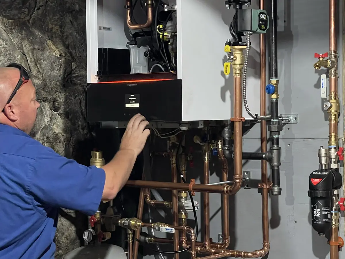 A.J. LeBlanc Heating technician performing a tune-up on a Viessmann wall-hung condensing boiler with multi-zone copper manifold and Taco circulator in Southern NH