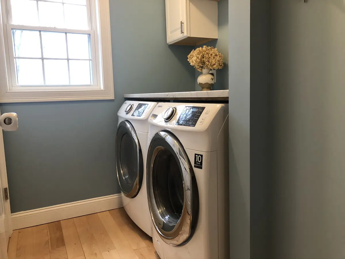 White front-load washer and dryer pair installed in a Southern NH laundry room with quartz counter above by A.J. LeBlanc Heating