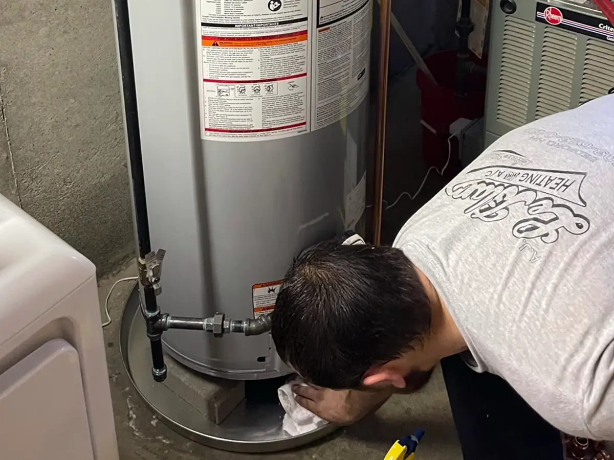 A.J. LeBlanc technician repairing a leaking water heater in a New Hampshire home, the kind of leak a smart water shutoff helps prevent